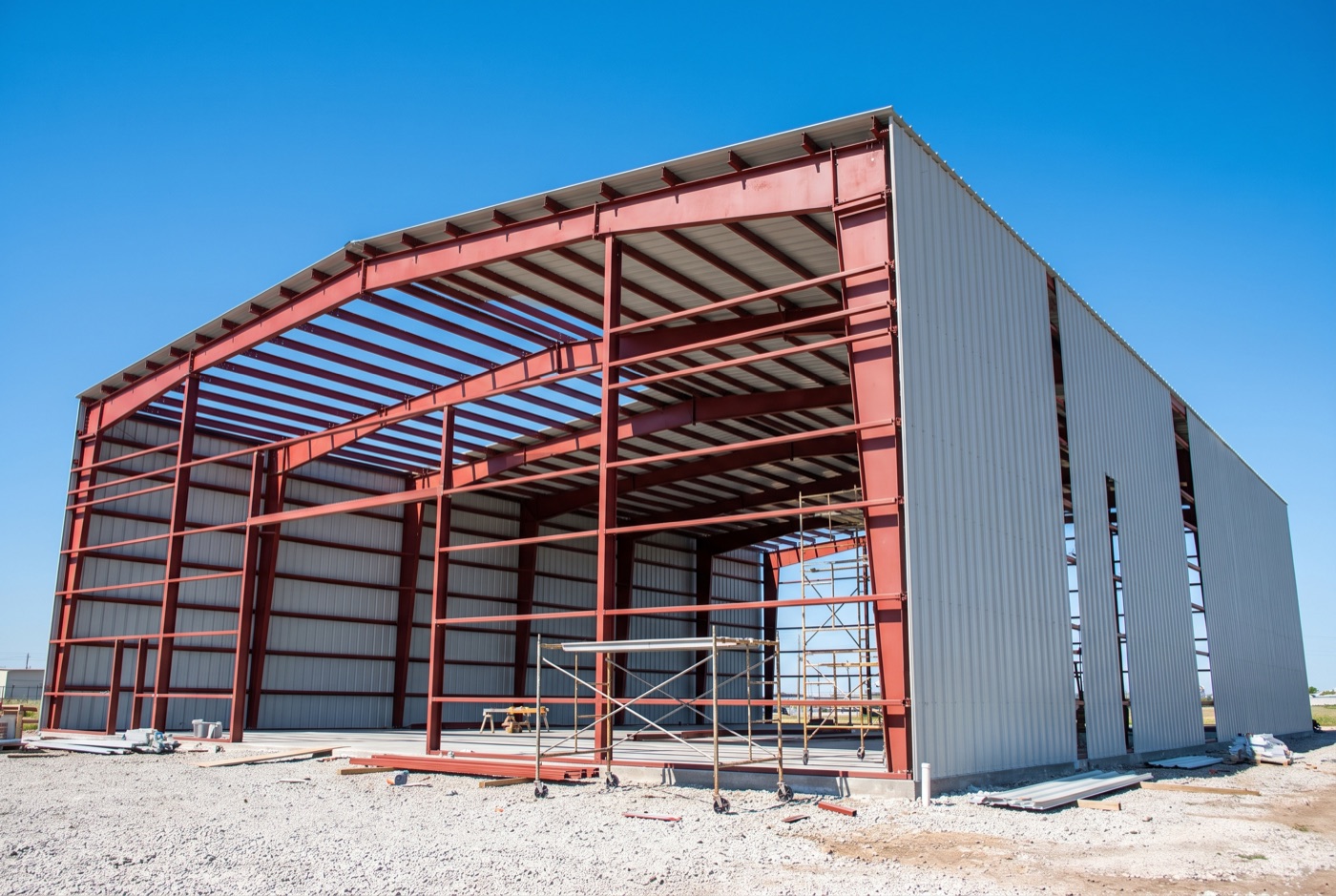 Structural steel frame of a metal building with rigid frames, purlins and girts, partway through cladding